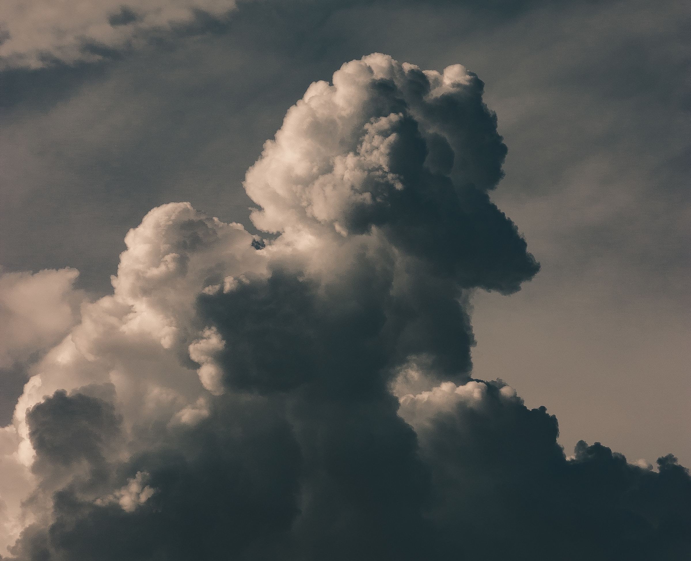 Cumulus cloud getting taller than it is wide with a moody sky in background.